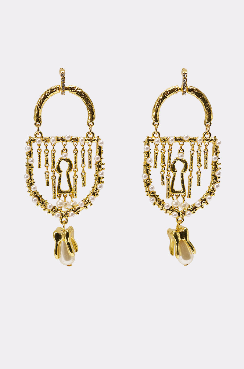 The UNLOCK ME EARRING is a pair of ornate gold statement earrings with keyhole-shaped cutouts, dangling gold and pearl-like beads, and intricate detailing shown against a white background. 0