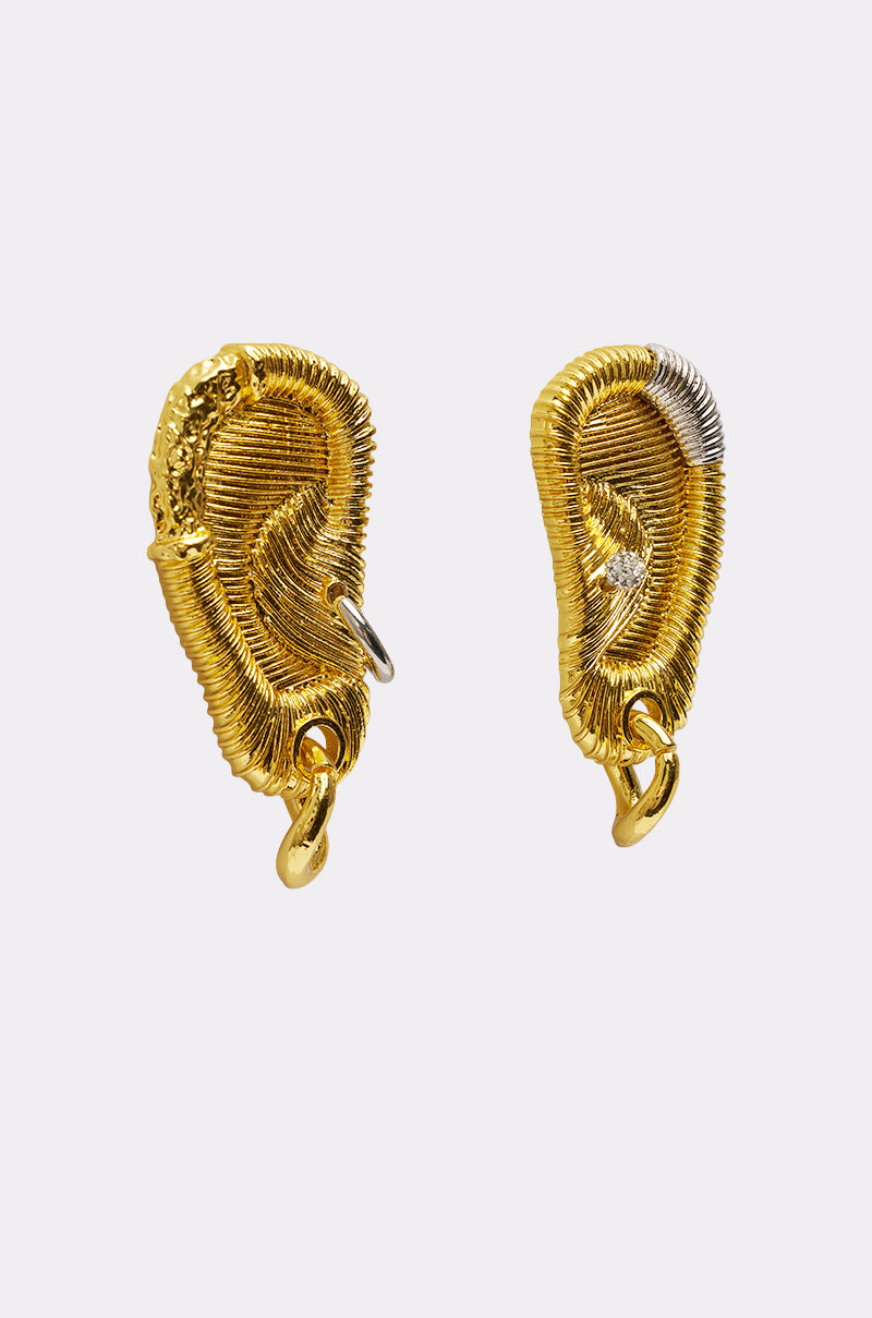 The HEARD U EARRING features two mismatched gold statement earrings shaped like human ears, accented with textured wire, small metallic rings, and a silver accent for a mixed-metal look, displayed on a plain light gray background. 3