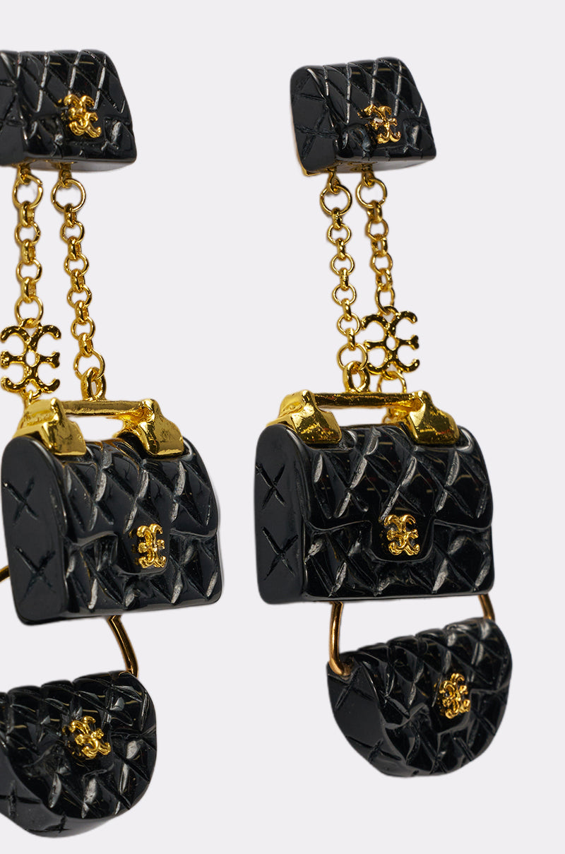 The GET ME A BAG EARRING features black quilted purse-shaped statement earrings with gold details and chain links. With a glossy finish and luxurious detailing, these bold earrings elevate any look. 3