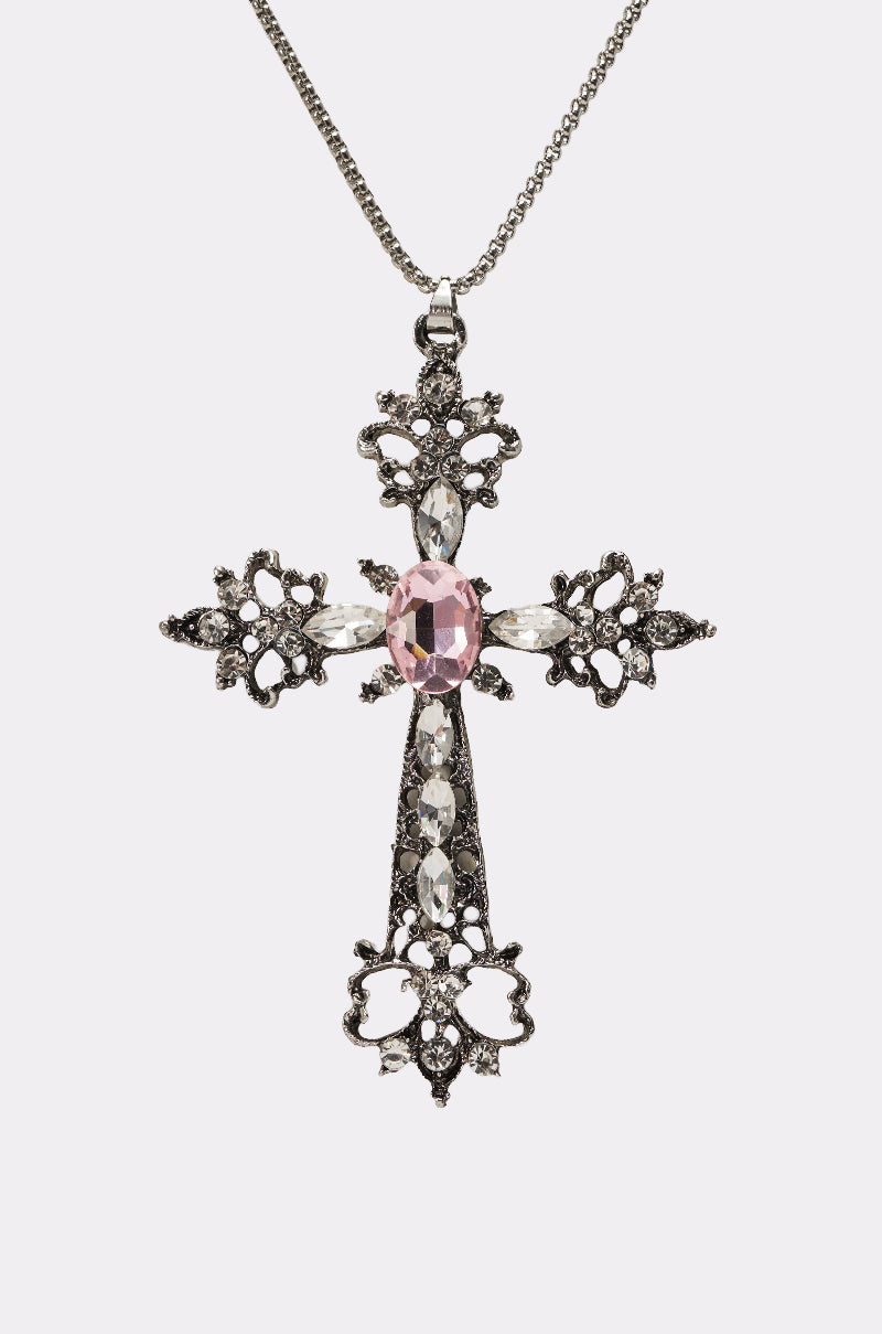 The LEXI NECKLACE is a gothic-chic silver cross pendant with ornate details, a central large pink gemstone, clear rhinestones along the arms, and hangs from a delicate chain. 4