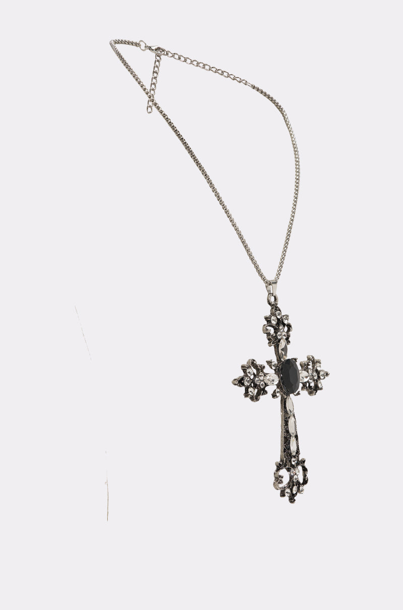 The KIM NECKLACE features a dark-romantic silver cross pendant, ornately designed and embellished with black and clear stones, shown against a white background. 2