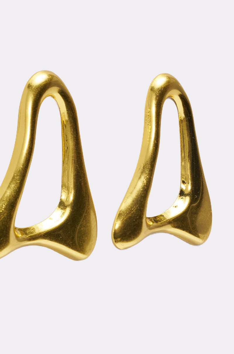 The MOD GAL EARRING features two abstract, asymmetrical gold statement earrings with smooth, shiny surfaces, shown on a plain white background for a bold minimalist and sculptural look. 4
