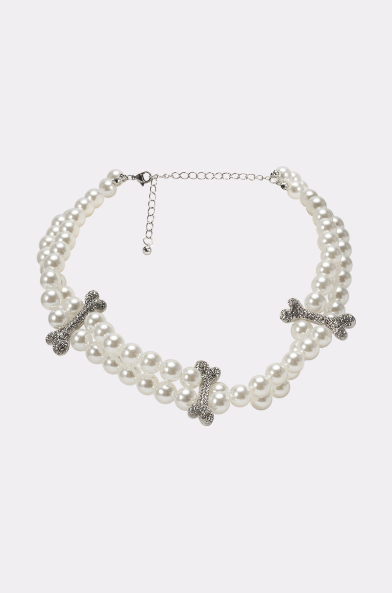 The ALIA PEARL NECKLACE is a double-stranded faux pearl necklace with three silver rhinestone bone charms and an adjustable chain clasp, shown on a plain white background. 0