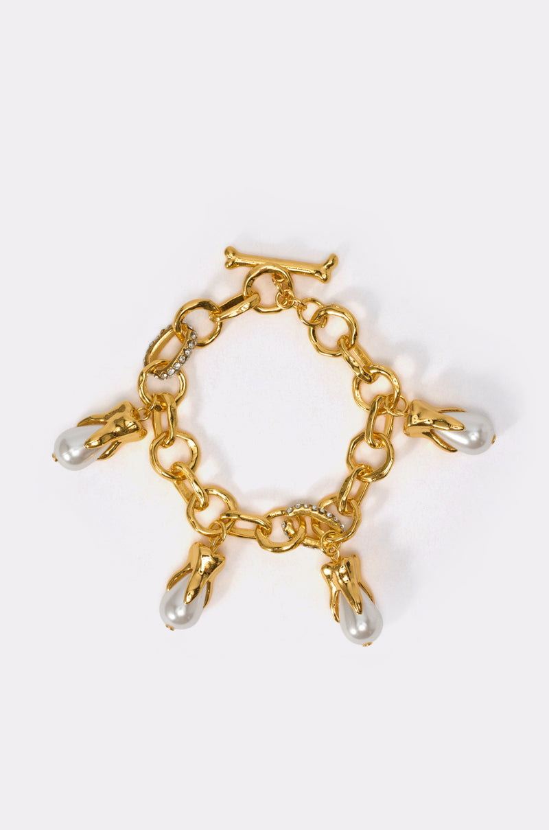 The DESERVE ME BRACELET is a gold chain link bracelet with a toggle clasp, adorned with four large white pearl-like charms—an elegant statement piece for any occasion, shown against a plain light background. 0