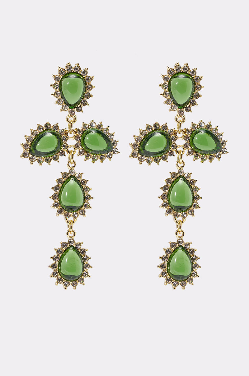 The GLORY EARRING is a pair of vintage-inspired, gold-tone statement earrings featuring cross shapes adorned with emerald-green oval and teardrop stones, each bordered by decorative gold and gemstone accents.