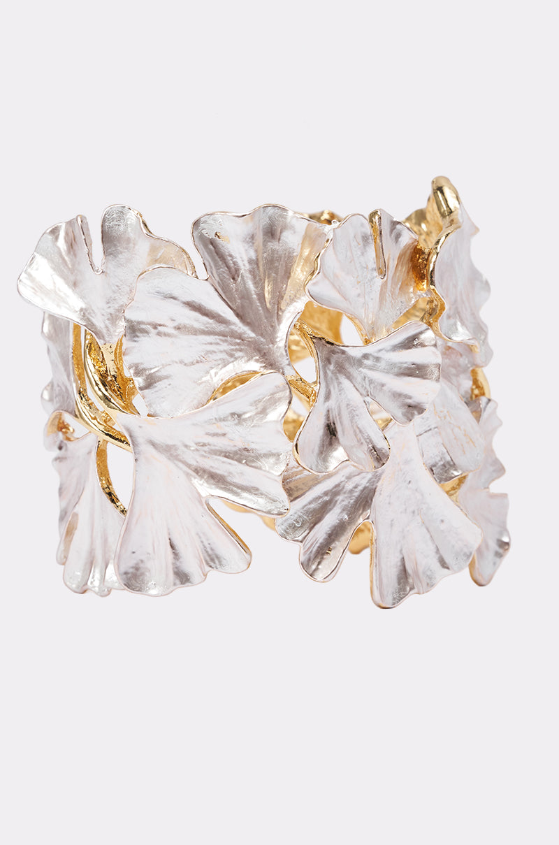 The IN BLOOM BRACELET showcases overlapping silver and gold-toned ginkgo leaves with detailed veining, offering a nature-inspired statement accessory or a unique choice for bridal jewelry.