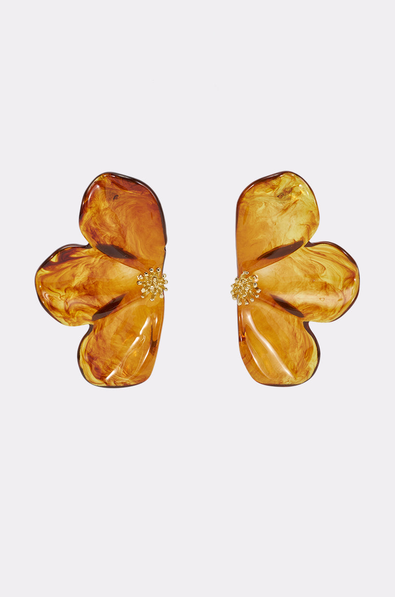 The RESIN FLORAL EARRINGS IN BROWN feature two amber-hued, brown marbled resin flowers accented with gold-tone centers, creating a bold floral statement. They are showcased against a plain white background.