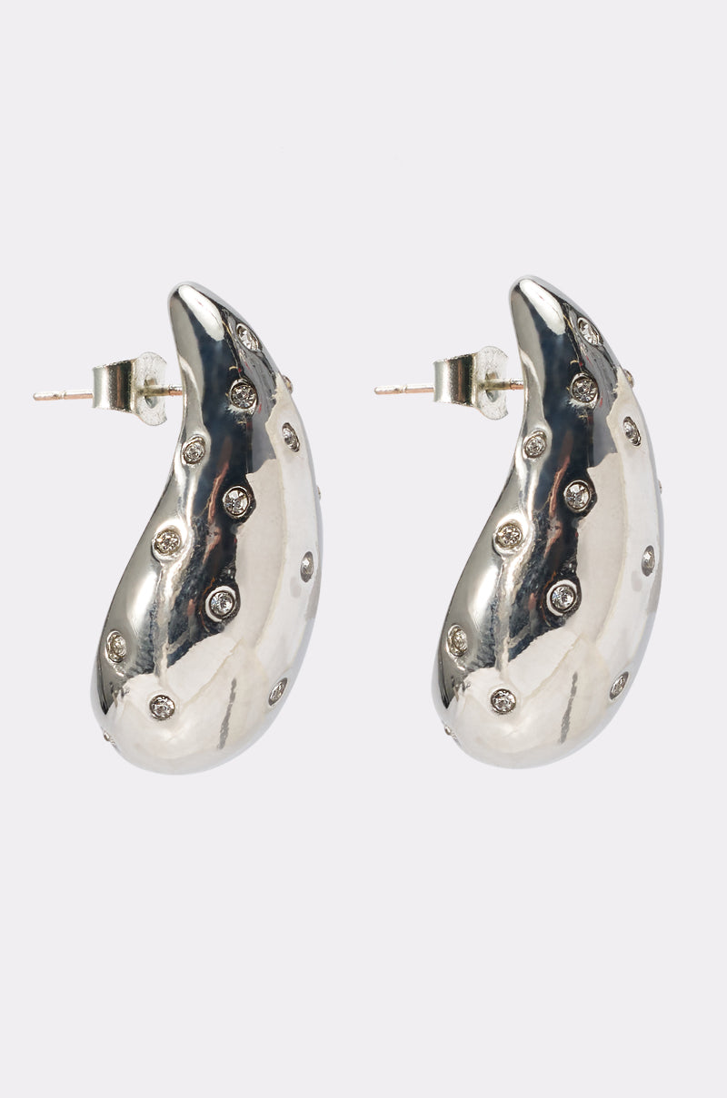 The ELLE EARRING features a shiny silver crescent shape adorned with small round studs, shown against a plain light background—an ideal statement piece for your next night out. 0
