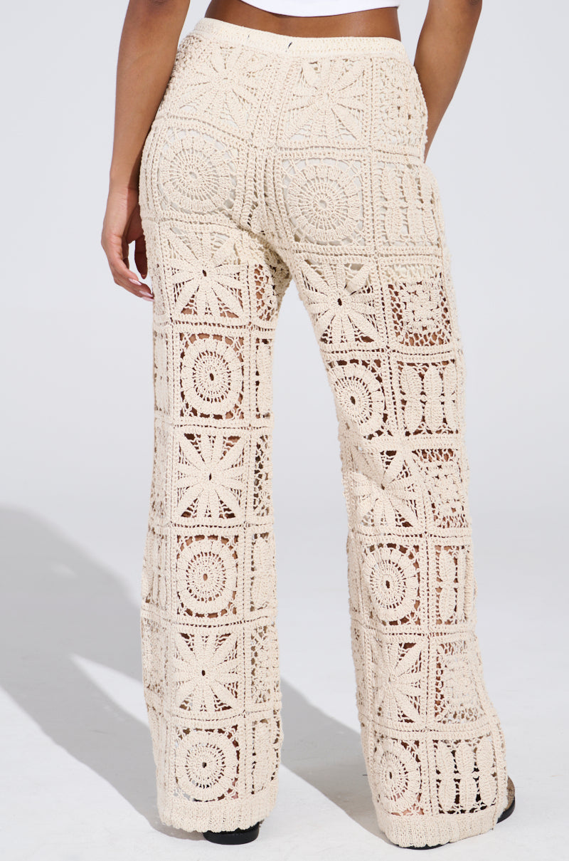 Wearing the Crochet Knit Pant, this look radiates a summer vibe with its elegant geometric pattern of squares and circles in natural tones. The slightly flared design stands out against the neutral background, seamlessly combining style and comfort.