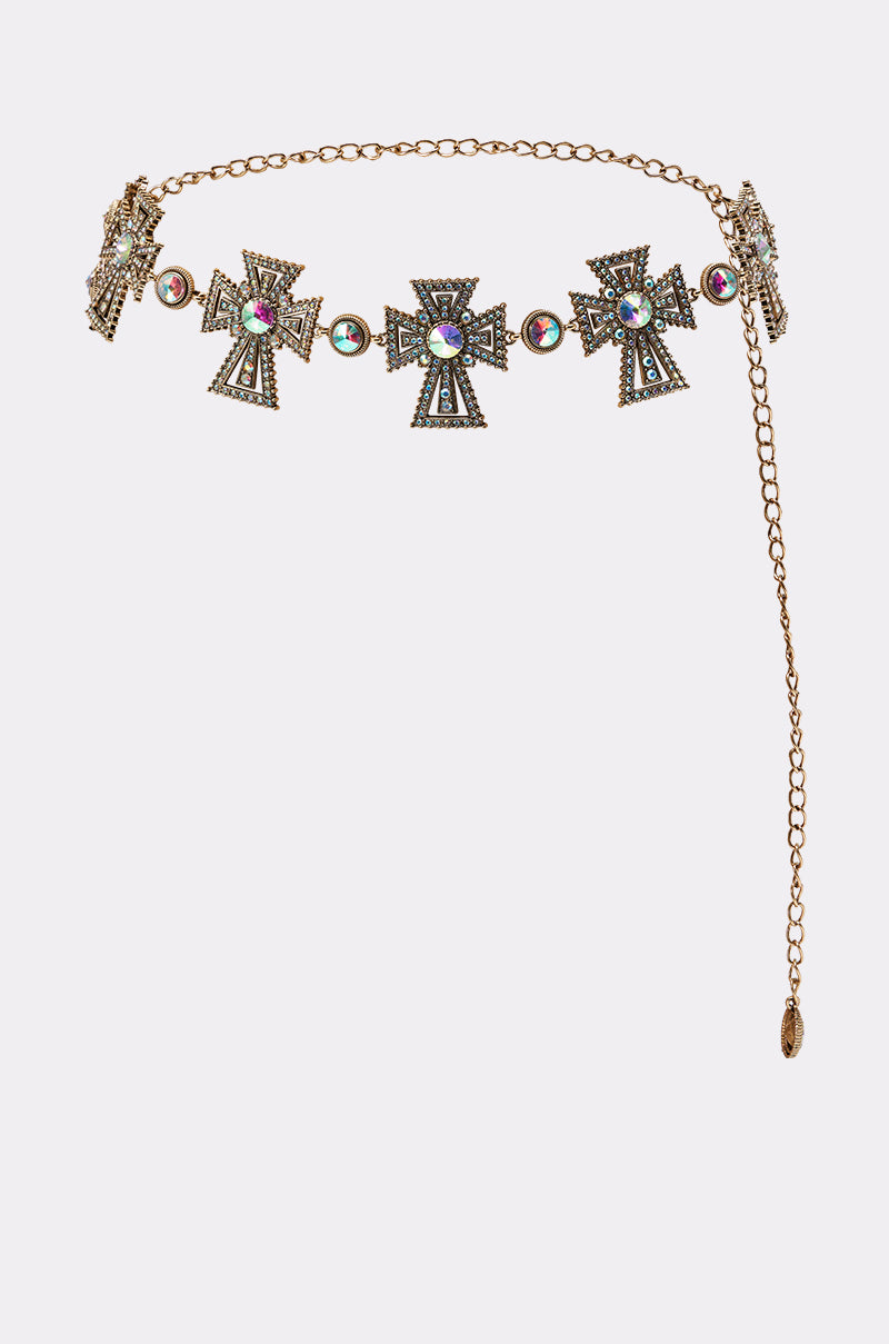 The IN ROME CHAIN BELT is a gold chain belt with ornate cross-shaped medallions accented by colorful gemstones, featuring an adjustable extended chain and clasp. This statement piece stands out against a light background. 1