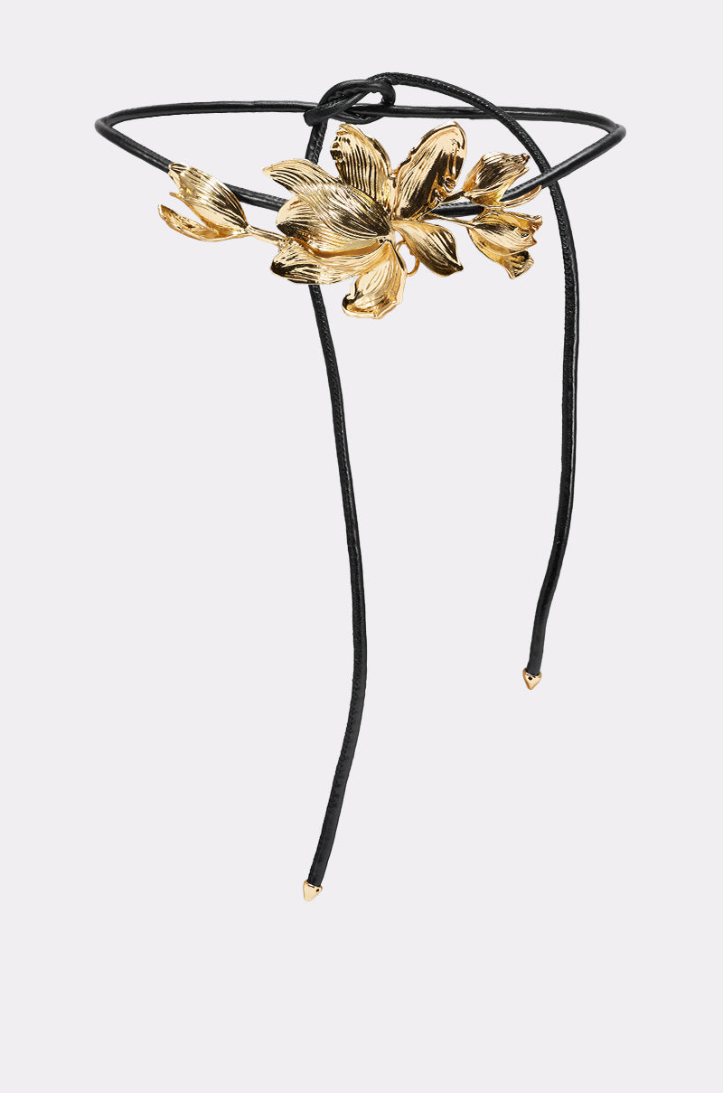 The PETAL POWER METAL DETAIL BELT features a gold floral centerpiece and two black cords with gold-tipped ends, shown against a plain white background. 2