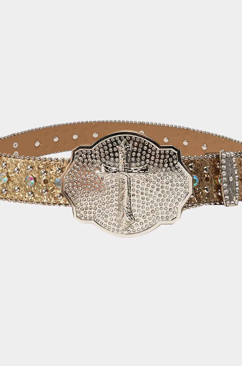The BIGGER IS BETTER BELT is a gold glitter western belt with shiny rhinestones and a large textured silver cross buckle, shown on a white background. 3