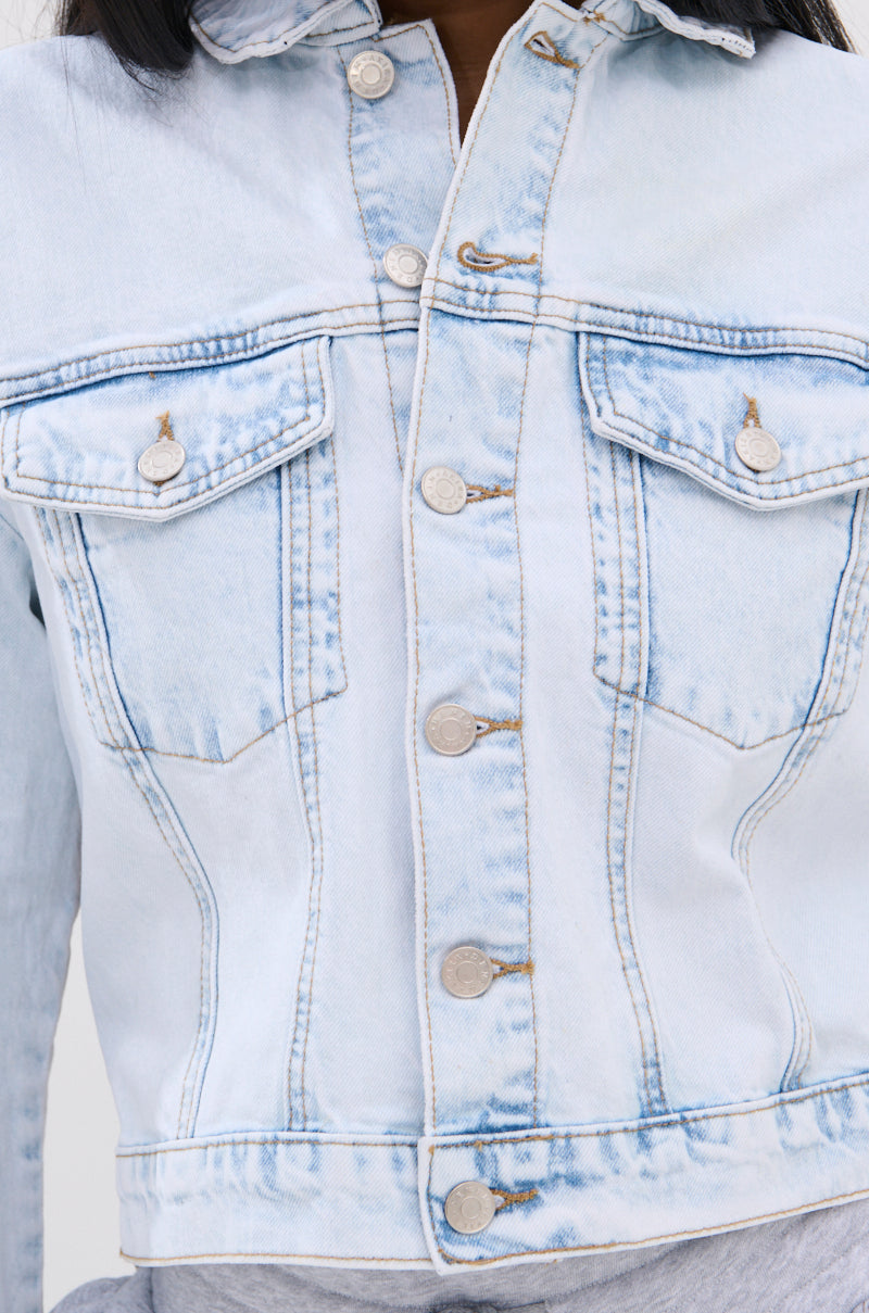 Close-up of the PARTY IN THE BACK DENIM JACKET, featuring acid-washed denim, silver buttons, two chest pockets, and silver-tone chains over a gray shirt. Only the torso and part of the neck are visible; the face is not shown.