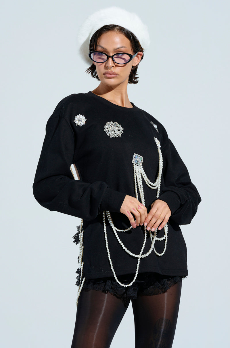 A person in an IT'S COMPLICATED PEARL TOP, black lace shorts, a white beret, and sunglasses poses against a light background, exuding modern fashion.