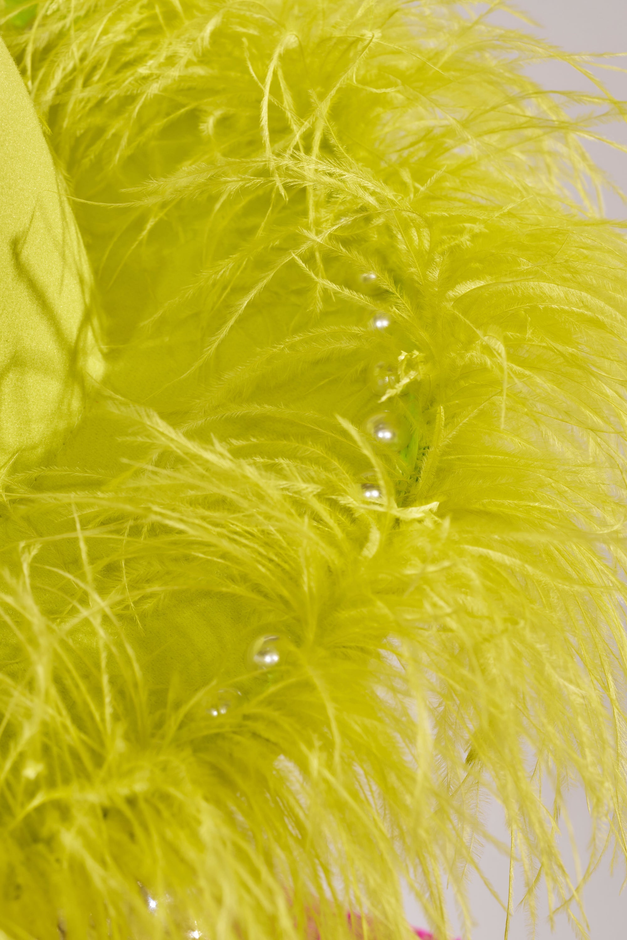 Close-up of the FEEL IT FEATHER BRIM HAT IN GREEN, showcasing vibrant green feathers and small silver beads for a textured, lively festival look. 2