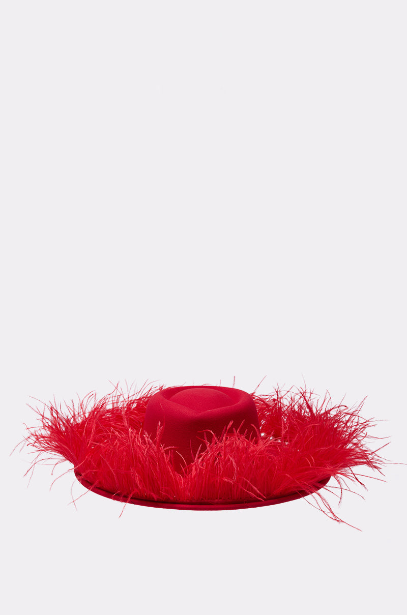 The LETS FLIRT FEATHER BRIM HAT features a bold red hue, wide brim, and a fringe of red feathers encircling the crown, set against a plain light backdrop—a striking statement piece. 1