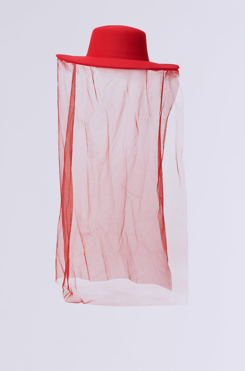 The TYPICAL ELEGANCE MESH OVERLAY BRIM HAT by AKIRA Label showcases a stunning red design, with a tonal mesh veil elegantly draping from the brim, all highlighted on a plain white background. 3