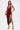 A woman stands confidently in the SOFIA FRINGE HIGH SLIT MIDI DRESS IN BURGUNDY, holding a gold clutch. She pairs it with gold high-heeled sandals and has straight, shoulder-length hair against a plain white background.