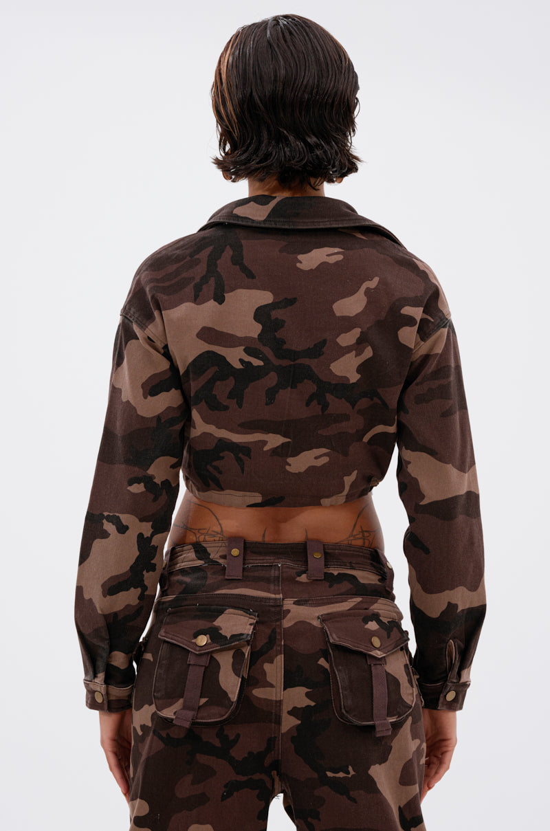 Person with short dark hair, seen from behind, wears the CANT SEE ME BROWN CAMO CROPPED BUTTON DOWN and matching pants. The camo shirt reveals part of their lower back and a tattoo above the waistband. 4