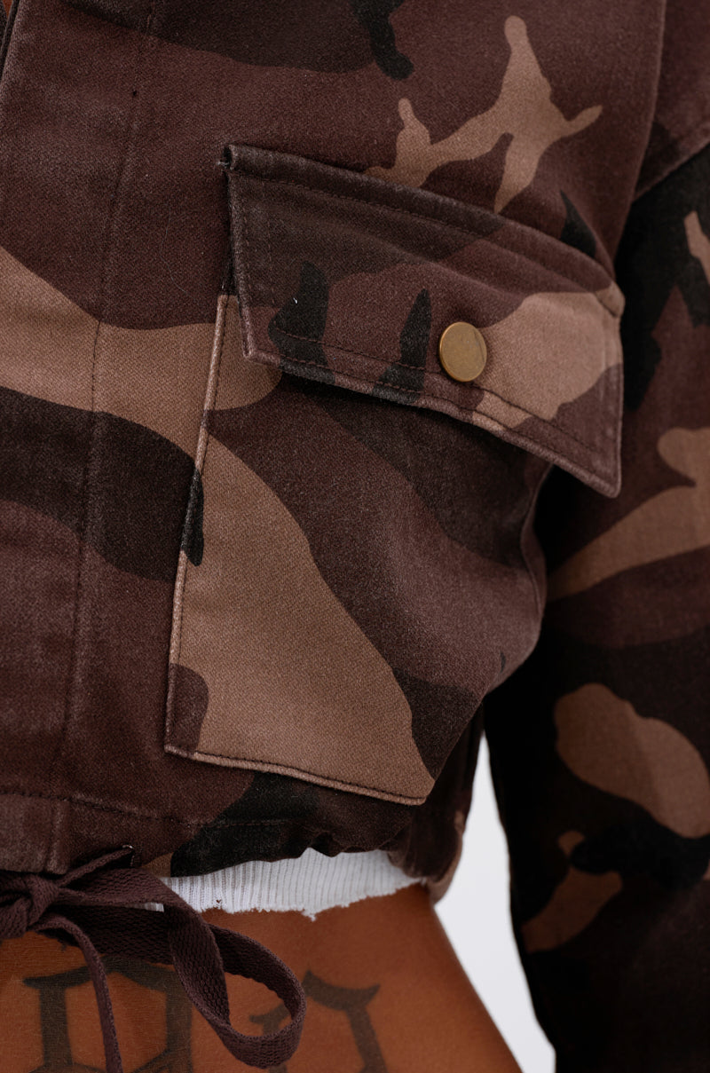 Close-up of the CANT SEE ME BROWN CAMO CROPPED BUTTON DOWN pocket with a gold snap, worn over a tattooed midriff. Part of the AKIRA Label collection. 8
