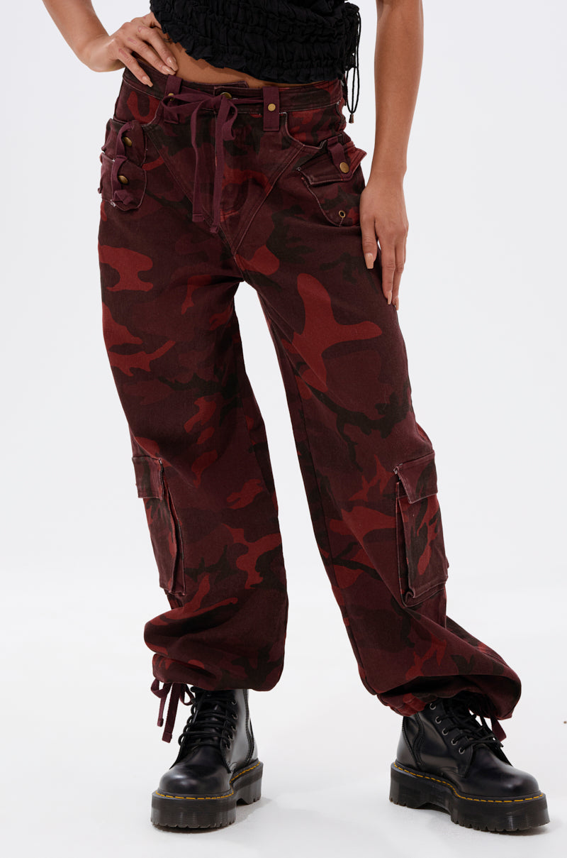 Wearing the CANT SEE ME BURGUNDY CAMP CARGO JOGGER with a matching belt, black platform lace-up boots, and a partially visible black top creates a stylish streetwear look. 1