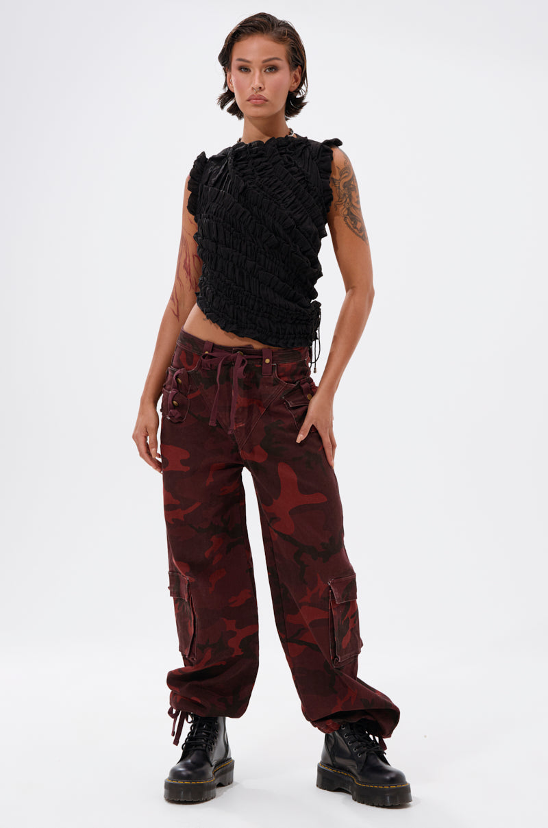 A person with short brown hair wears a textured black sleeveless top, CANT SEE ME BURGUNDY CAMP CARGO JOGGER pants, and black combat boots, standing confidently against a plain white background. 7