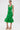 A woman models the LET'S GO TO THE BEACH RUFFLE MIDI DRESS IN GREEN, a sleeveless, fitted dress with a smocked bodice and ruffled hem. She pairs it with hoop earrings and nude platform sandals with ankle straps against a white background.