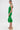 A woman stands sideways in the LET'S GO TO THE BEACH RUFFLE MIDI DRESS IN GREEN, featuring textured eyelet lace and a ruffled hem. She wears gold hoop earrings and beige platform sandals with ankle straps, set against a plain white background.