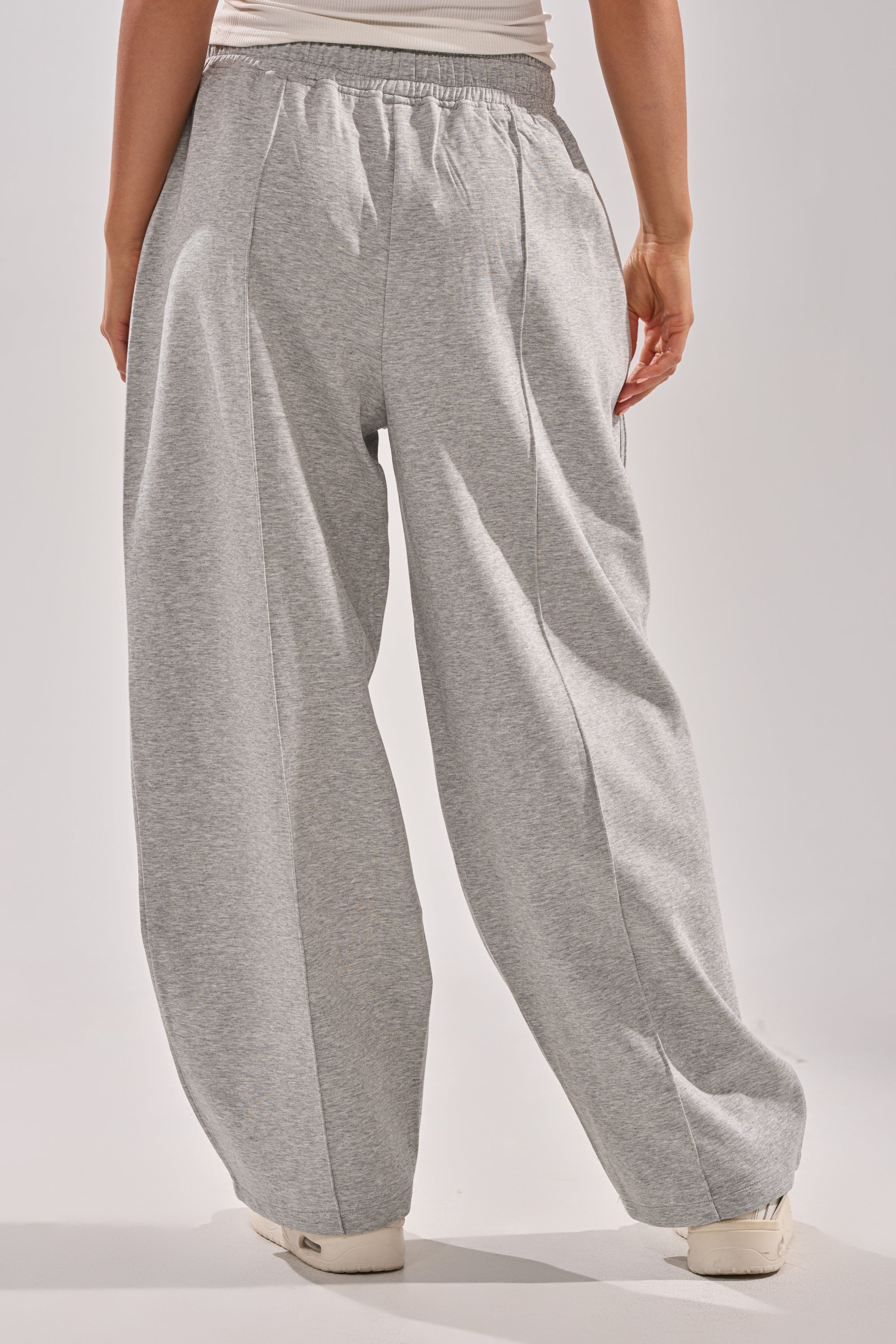 A person is shown from the back on a plain light background, wearing loose-fitting GET WITH IT WIDE LEG CARGO JOGGERS in grey with white sneakers. 4