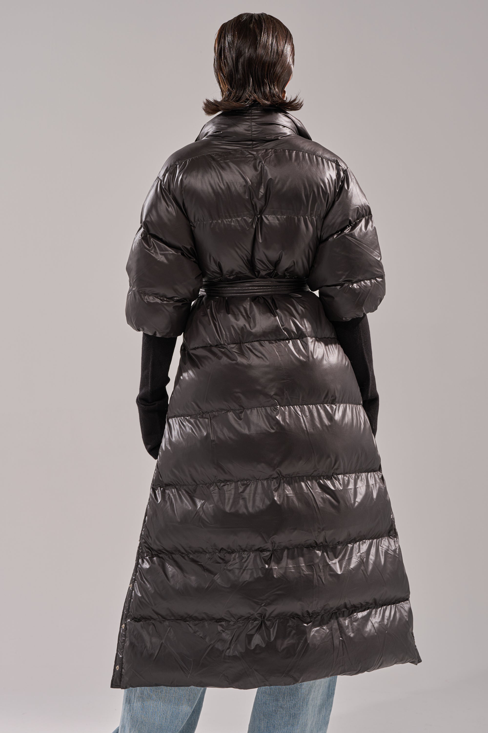 Person stands with their back to the camera, wearing the POPPIN OFF TEARAWAY PUFFER, black gloves, and light blue jeans against a plain gray background.