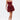 A woman stands confidently in the BELINA LACE MINI DRESS WITH BUBBLE SKIRT IN BURGUNDY, featuring a strapless sheer bodice and voluminous skirt. She holds a gold clutch, wears platform heels, and her hair is slicked back against a white background.