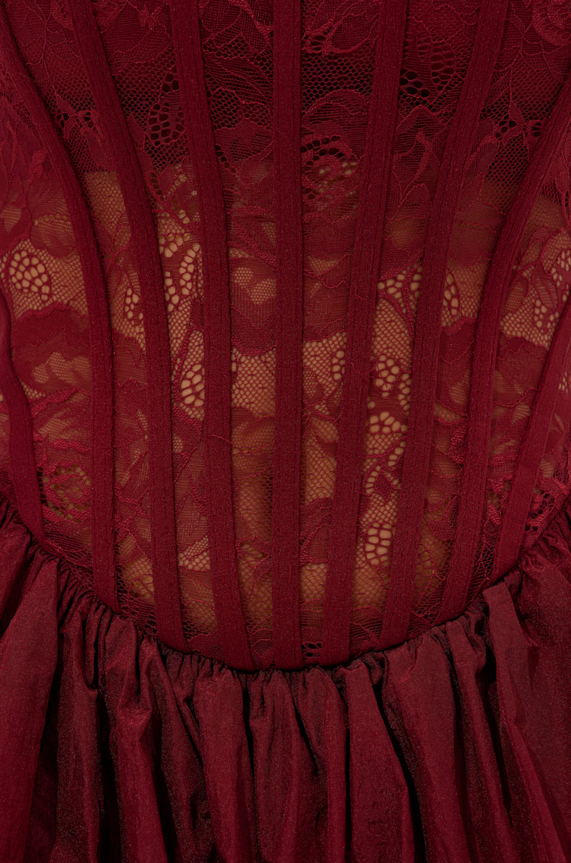 Close-up of the BELINA LACE MINI DRESS WITH BUBBLE SKIRT IN BURGUNDY, showcasing sheer floral lace, vertical boning, and a gathered tulle bubble skirt at the waist.