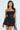 A woman with long, wavy hair poses against a light background, wearing the BELINA Lace Mini Dress featuring a strapless design, sweetheart neckline, and bubble skirt. She accessorizes with a small handbag.