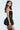A woman with long black hair wears the BELINA LACE MINI DRESS featuring a sweetheart neckline and lace details, complete with a voluminous bubble skirt. She stands in profile, looking at the camera, holding a small bag against a plain white background.