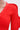 A close-up of a person wearing the COOLEST ON THE BLOCK MINI DRESS IN RED, featuring ribbed knit fabric and ripple sleeves, with a silver chain necklace. Only their neck, shoulder, and upper arm are shown against a plain background.