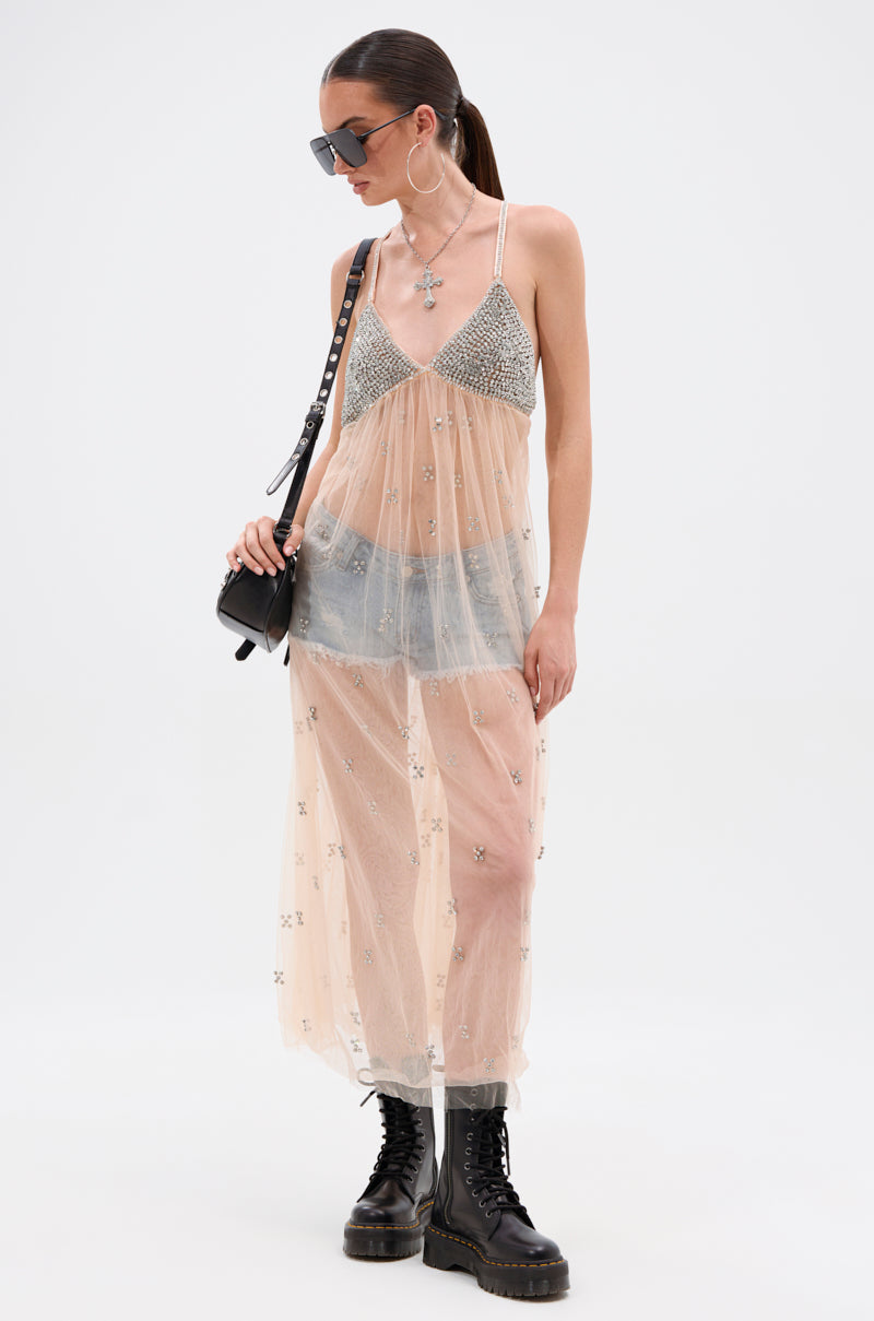 A woman wears sunglasses and the DO YOU BELIEVE IN LOVE RHINESTONE MESH MIDI DRESS over a sparkly bralette and denim shorts, accessorized with a black shoulder bag, hoop earrings, and black lace-up combat boots.
