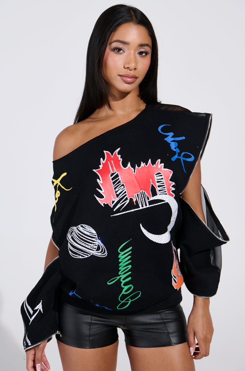 A person with long hair wears an oversized black Deep Thoughts graphic sweatshirt made from cotton-blend fabric, showcasing colorful abstract designs like a cityscape, planet, and swirling shapes. They're also in black shorts against a plain light gray background.