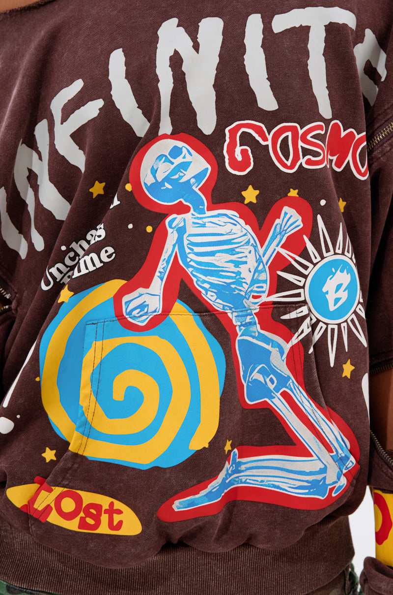 A close-up of the INFINITE COSMOS OVERSIZED GRAPHIC SWEATSHIRT featuring cosmic graphics—a blue skeleton, yellow and blue spiral, stars, and bold statements like "INFINITY" and "Unchain's time"—on a brown background.