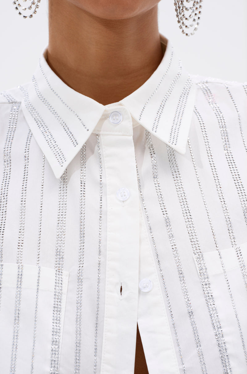 Close-up of a person wearing the ONTO THE NEXT EMBELLISHED BUTTON DOWN TOP IN WHITE, featuring vertical silver sequin details and large, dangling silver earrings. The face is partially out of frame. 6