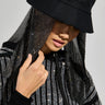 A person wearing the STRAIGHT DRIPPIN BUCKET HAT IN BLACK, featuring rhinestone detailing and a sparkling, beaded veil that partially conceals their face. Their matching black hoodie is adorned with similarly shimmering patterns.