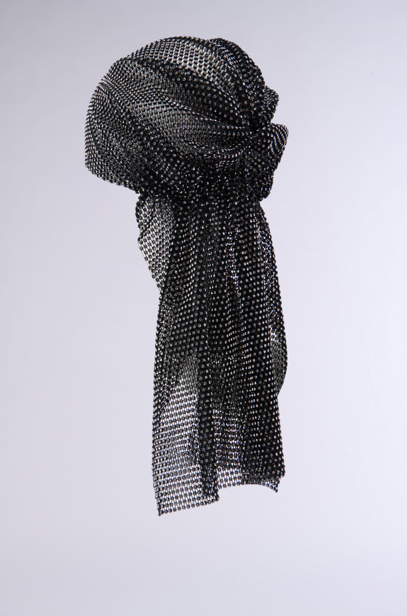 The ELEGANCE IS EARNED HEADPIECE, featuring a black mesh scarf with metallic accents and rhinestone mesh, is intricately tied into a stylish knot against a plain white background. The lightweight, semi-transparent fabric gives it a delicate and elegant appearance. 8