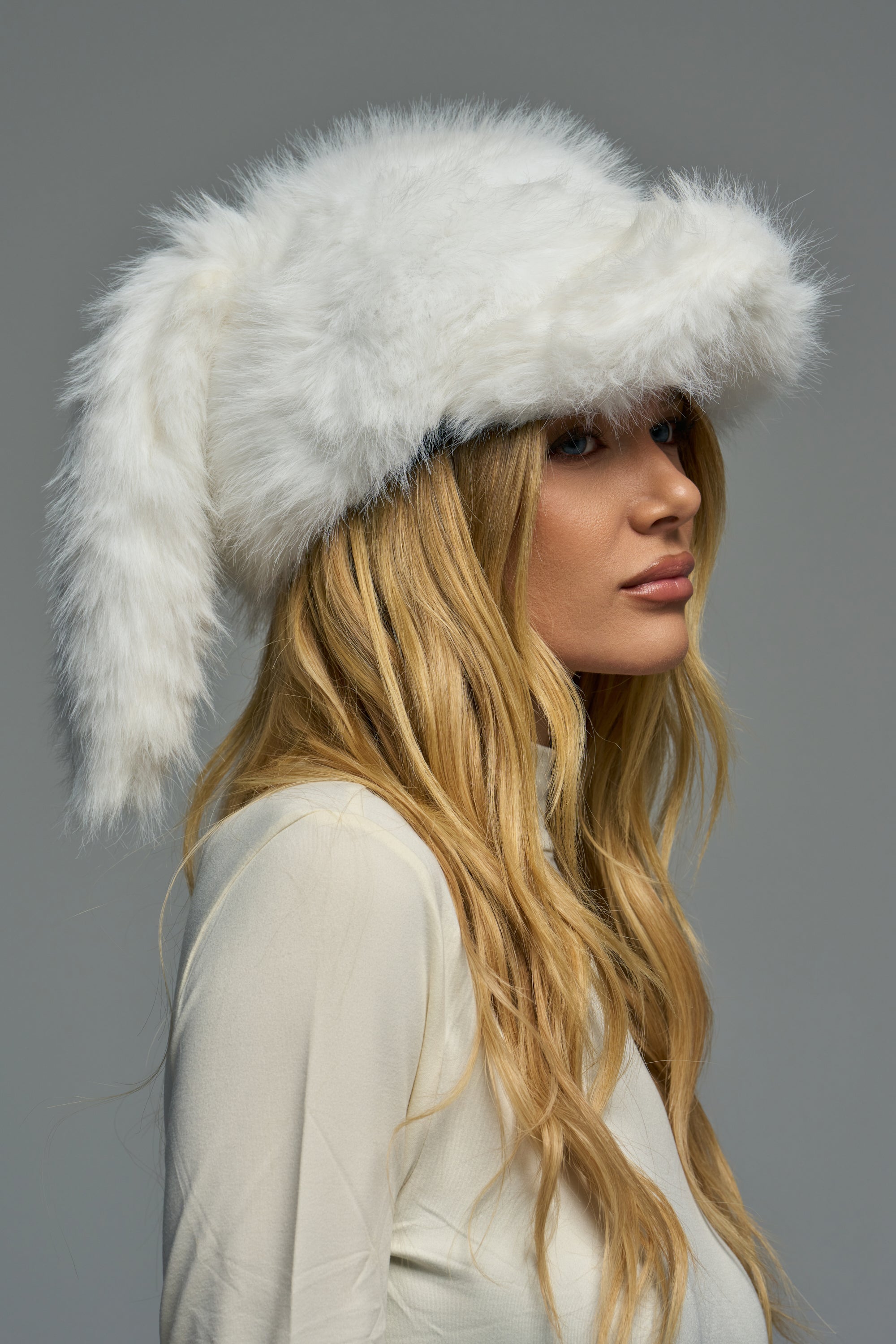 A person wearing a white CUTIE BUNNY EAR HAT, featuring long, floppy bunny-style ears.
