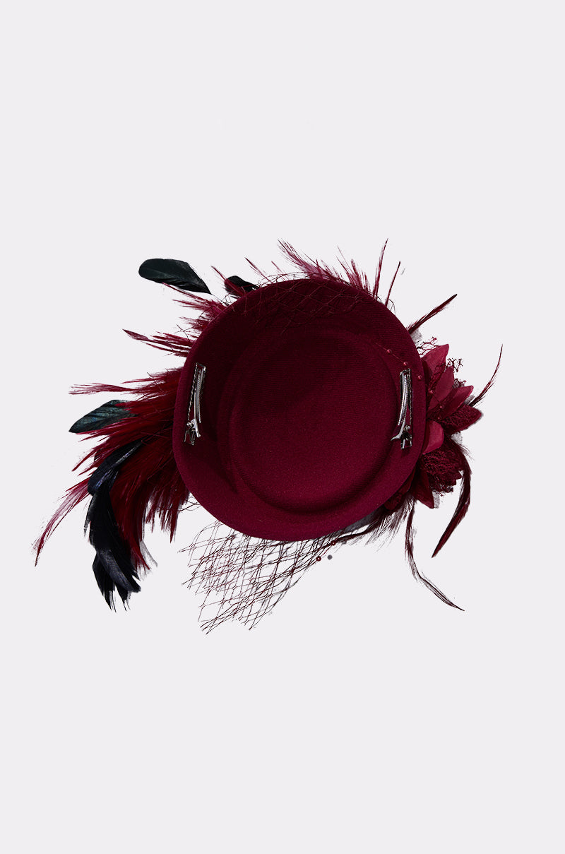 The TOP OF THE DAY CLIP ON FASCINATOR, featuring maroon and black feather plumes, silver clips, a netted veil, and floral accents, is shown from above on a plain light background. This elegant accessory adds sophistication to any outfit. 6