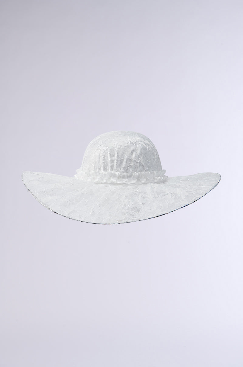 The I AM IT LACE HAT, featuring a wide brim and delicate floral lace design, stands elegantly against a plain light gray background.