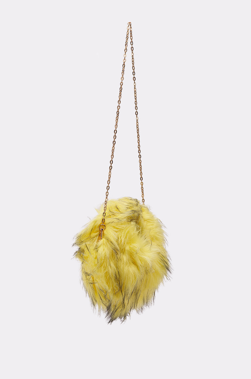 The ELLIE FAUX FUR PURSE, a round and fluffy yellow bag with black streaks, hangs from a thin gold chain strap against a plain white background. 2