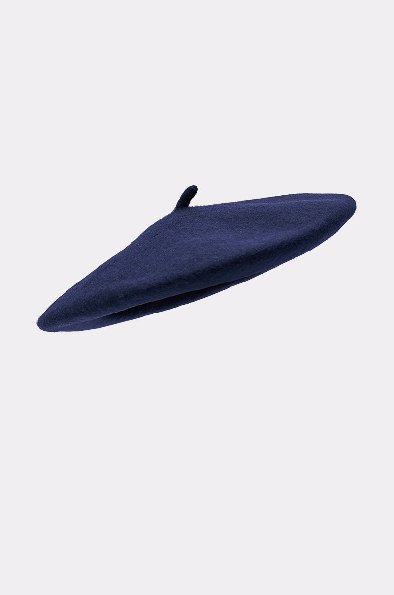 The TOO COZY NAVY BERET, a classic Parisian accessory featuring a small stem on top, is displayed against a simple light gray backdrop. 2