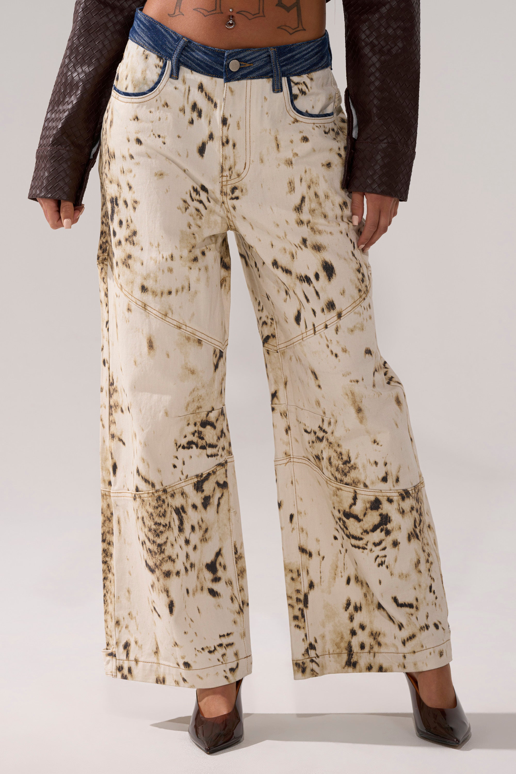 Person wearing BAMBI GIRLY WIDE LEG DENIM with a black spotted print, blue waistband and pocket details, plus brown pointed shoes and a dark long-sleeve top. Only the lower body is shown. 1