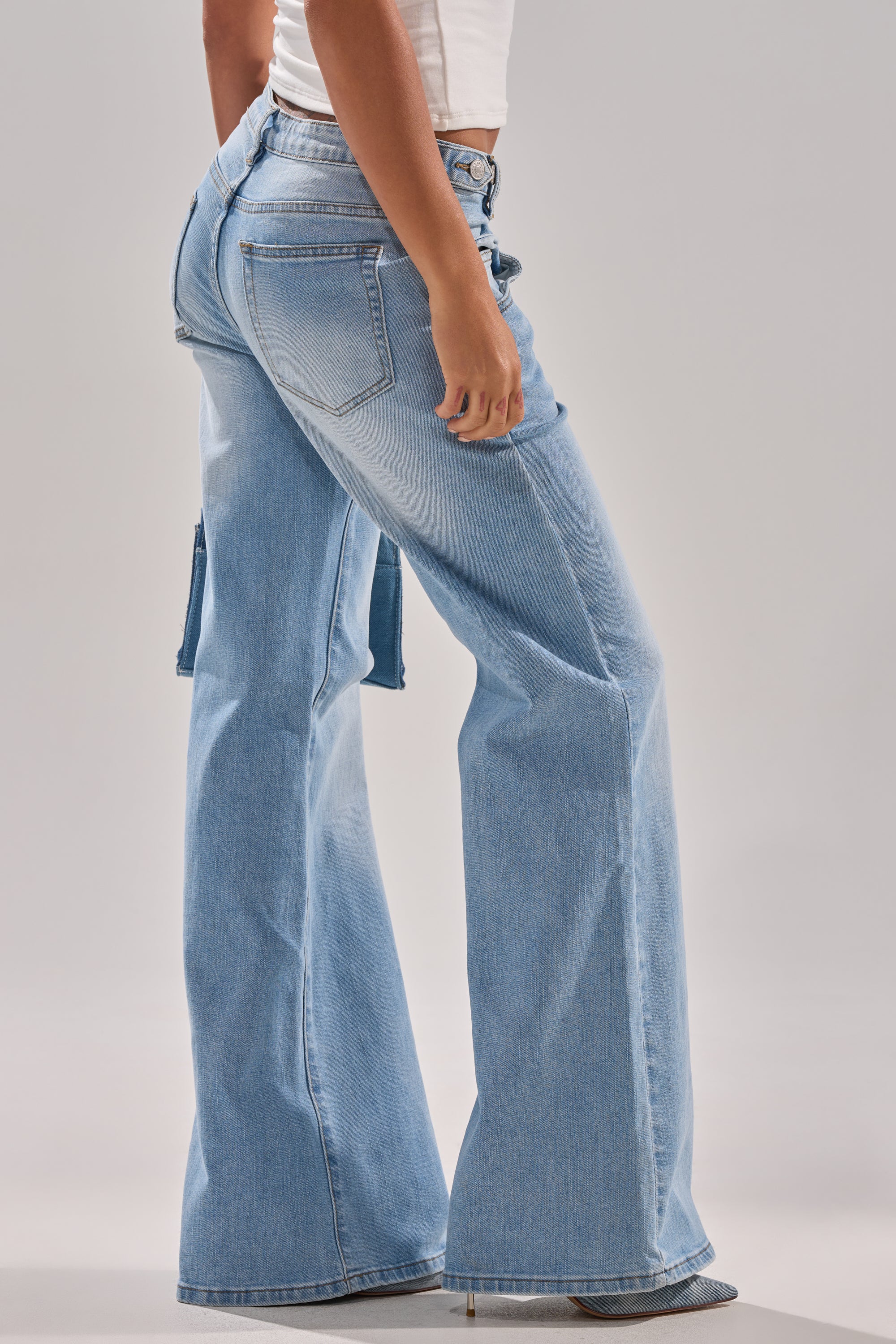 A person wearing the WON'T LOSE MYSELF WIDE-LEG BLUE DENIM jeans and a white cropped top stands sideways against a neutral background. 3