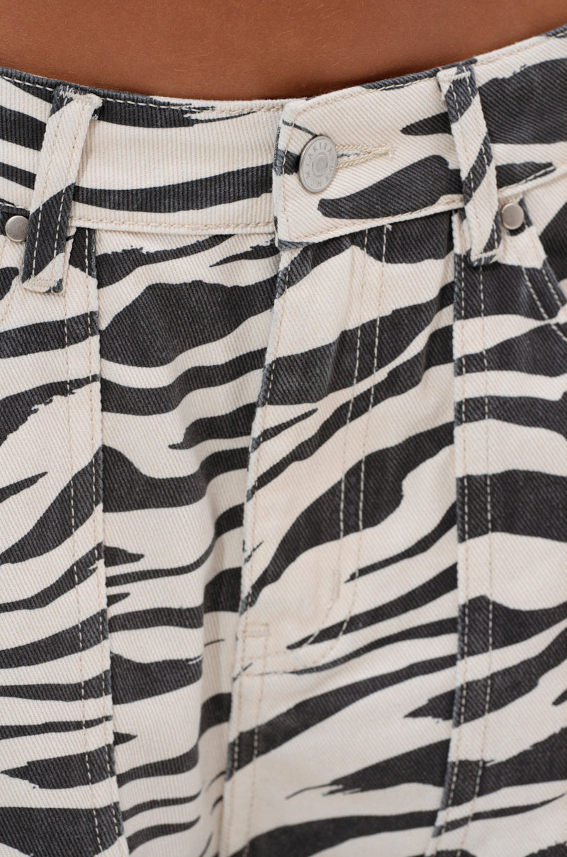 Close-up of the waistband and upper section of the ZEBRA LUXE BERMUDA SHORT, featuring zebra print, belt loops, silver button, and detailed seams.