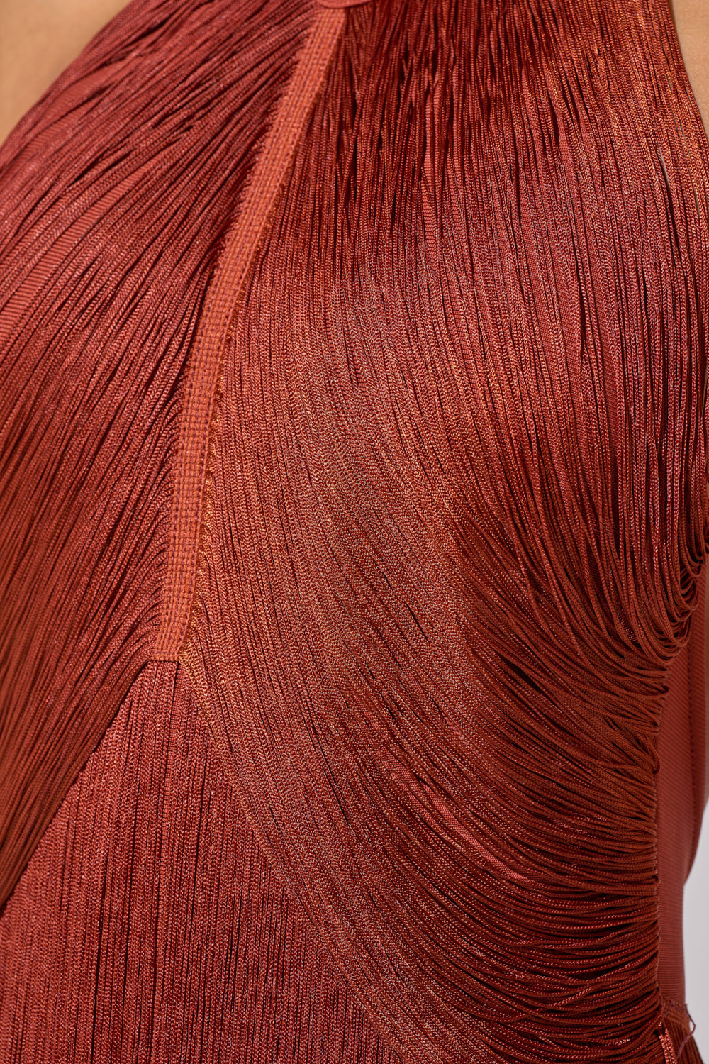 Close-up of the FORGET ME NOT FRINGE MAXI DRESS in rust, featuring a halter neck, fine textured pleats, seam detailing, and smooth shimmering fabric—an elegant choice for evening events. 9